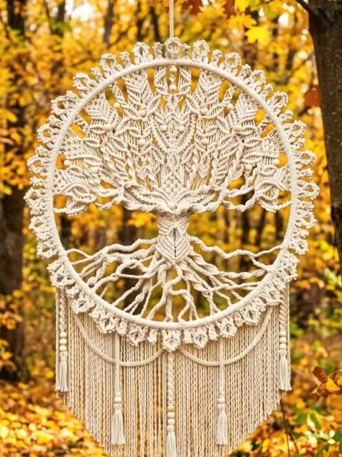 Beautiful macrame Tree of Life dreamcatcher hangs from a tree branch in a forest filled with golden autumn foliage. 🍂🍁👍 You can find more Tree of Life patterns on the YouTube channel: MACRAME SCHOOL #treeoflife #macrame #wallhanging #autumnvibes #dreamcatcher